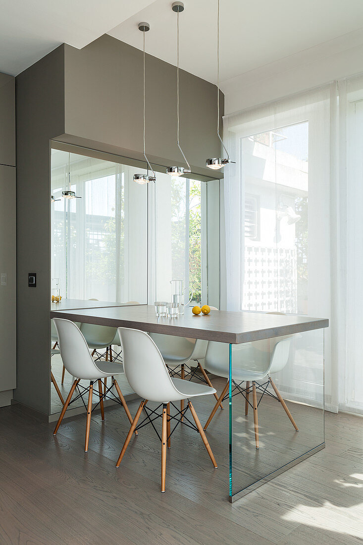 Frühstückstisch und Stuhlklassikern vor Fensterfront in Designerküche