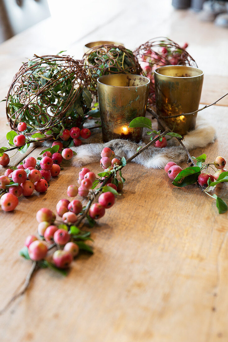 Natural arrangement with crab apples and tealights on wooden table