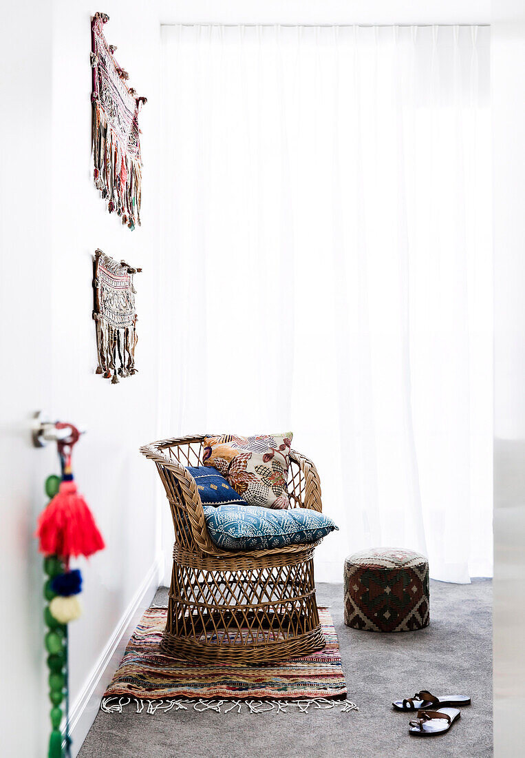 Wicker armchair with various pillows on a patchwork quilt