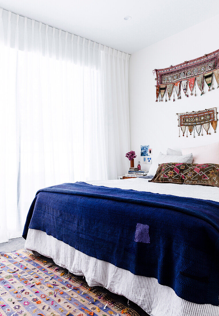 Blue bedspread on the bed with folkloric decoration