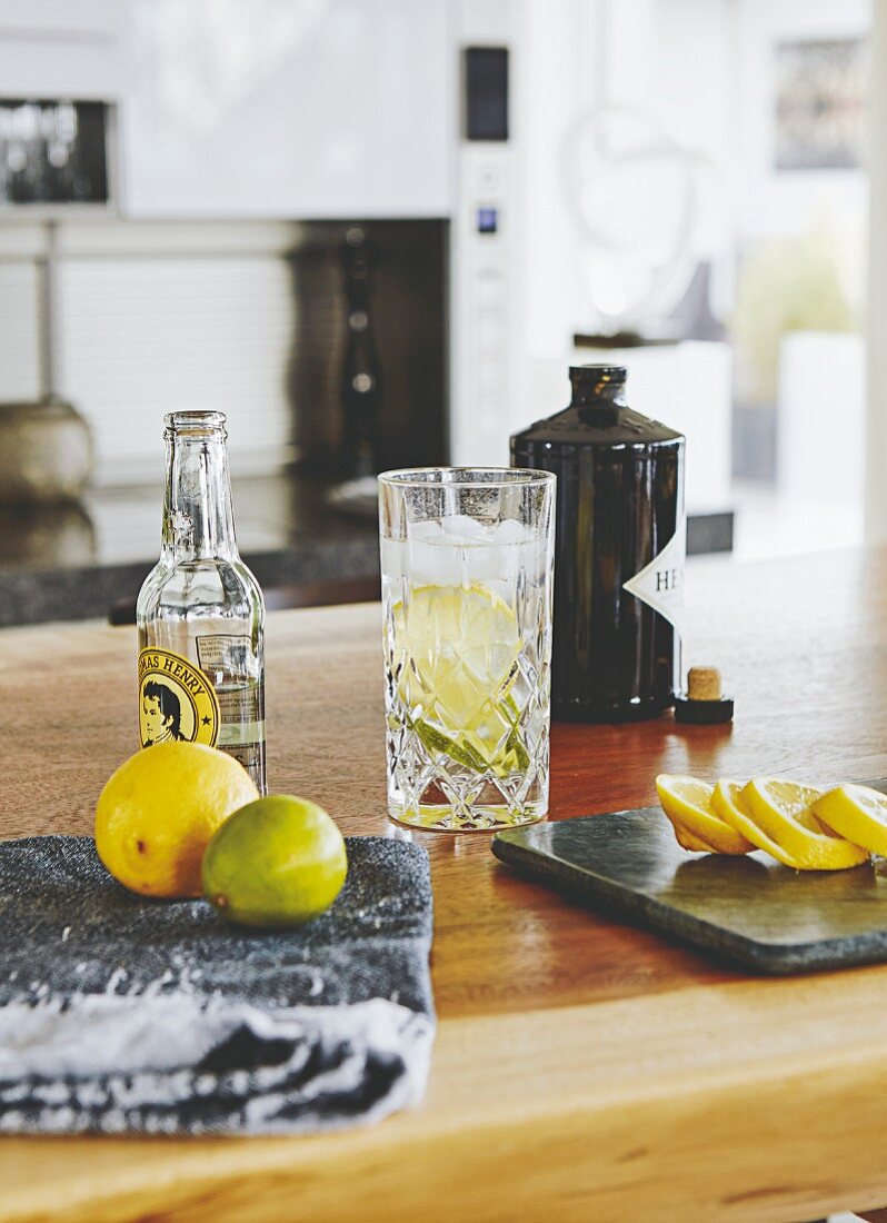 A gin and tonic with ingredients on a kitchen counter