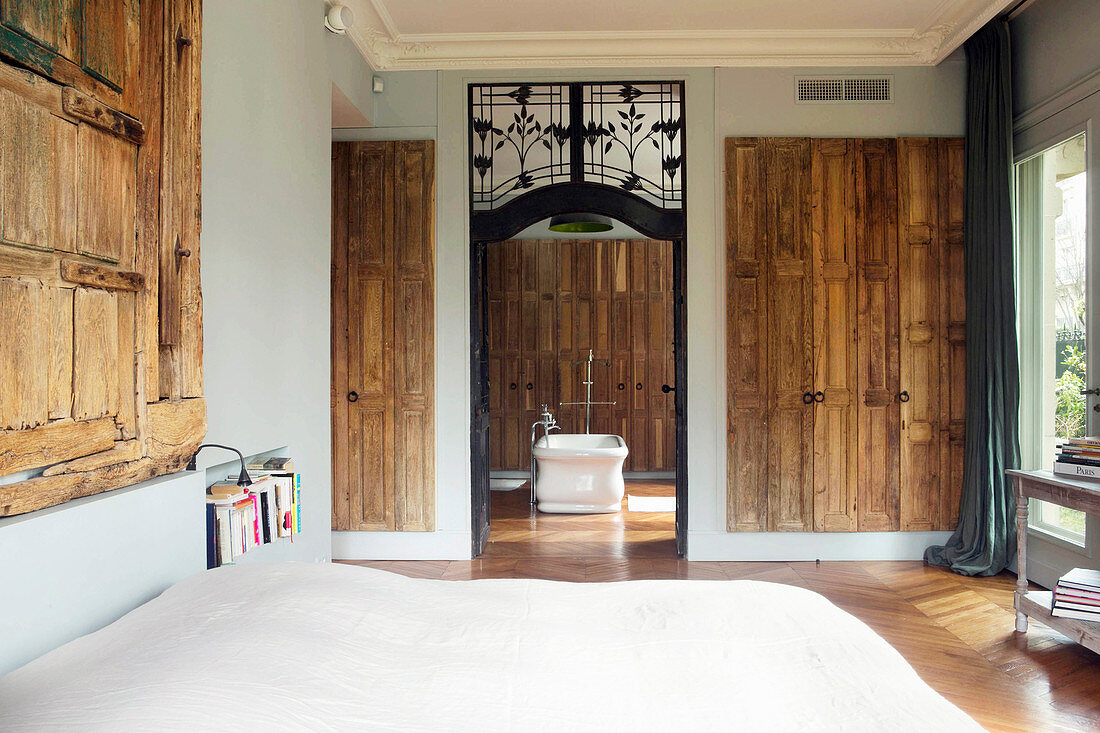 Old wooden doors on walls in bedroom with view into bathroom