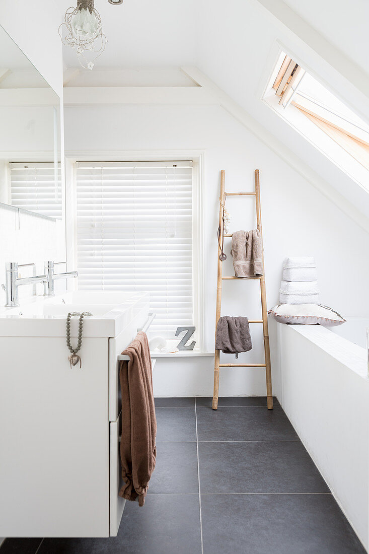 Towels on wooden ladder in modern attic bathroom