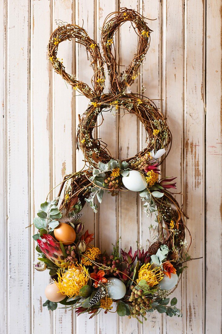Bunny-shaped Easter wreath decorated with flowers on wall