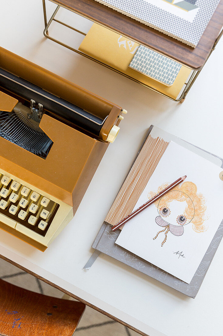 Postkarte und Notizbuch neben einer alten Schreibmaschine