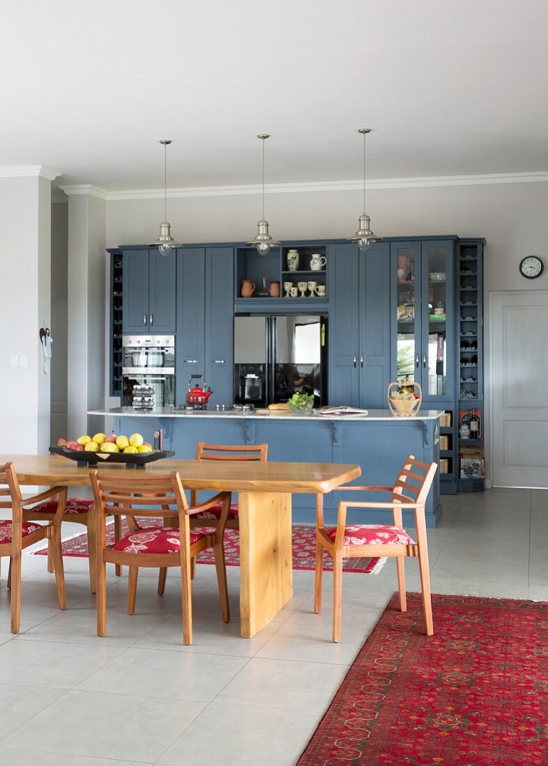 Solid wooden furniture in dining area of open-plan country-house kitchen with blue fronts
