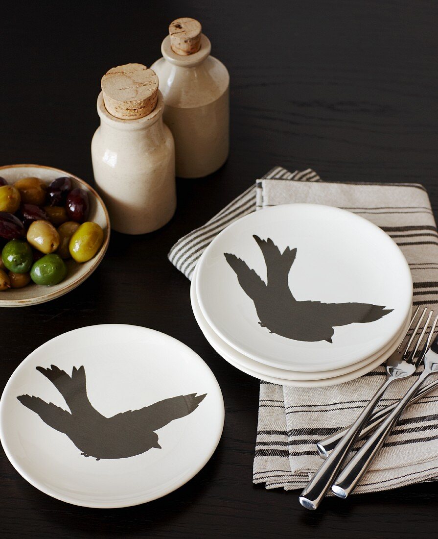 weiße Teller mit schwarzen Vögeln auf gestreiften Servietten