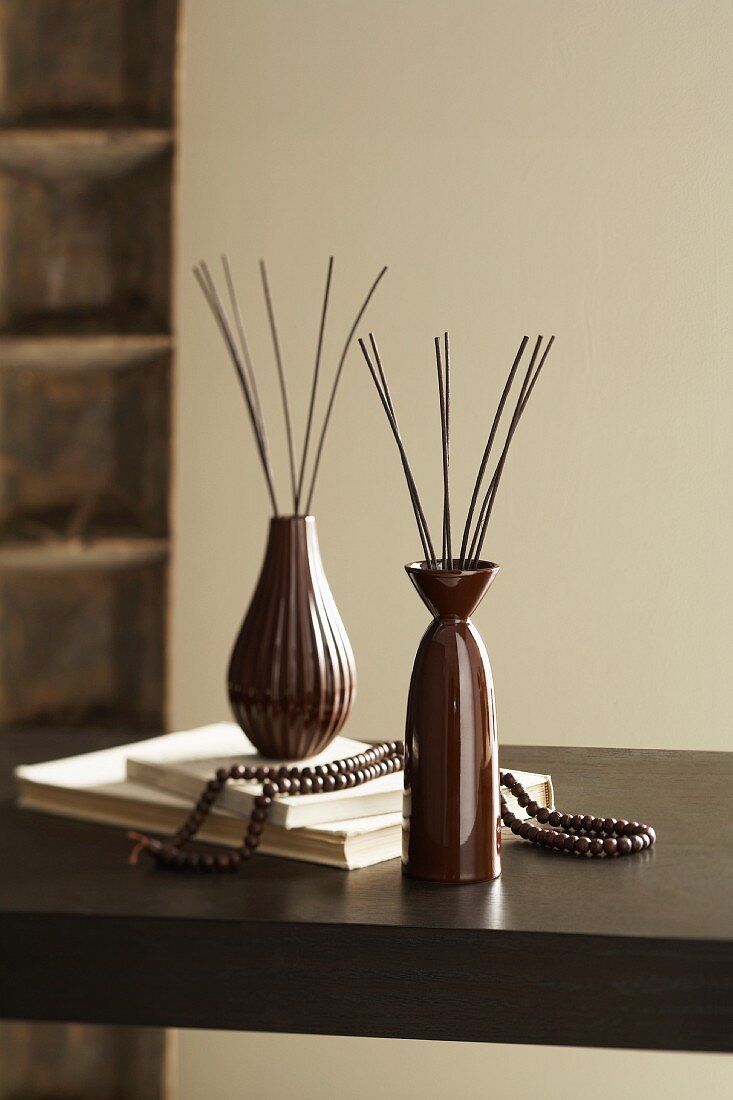 Braune Vasen mit Stäbchen als Raumparfums auf dem Tisch