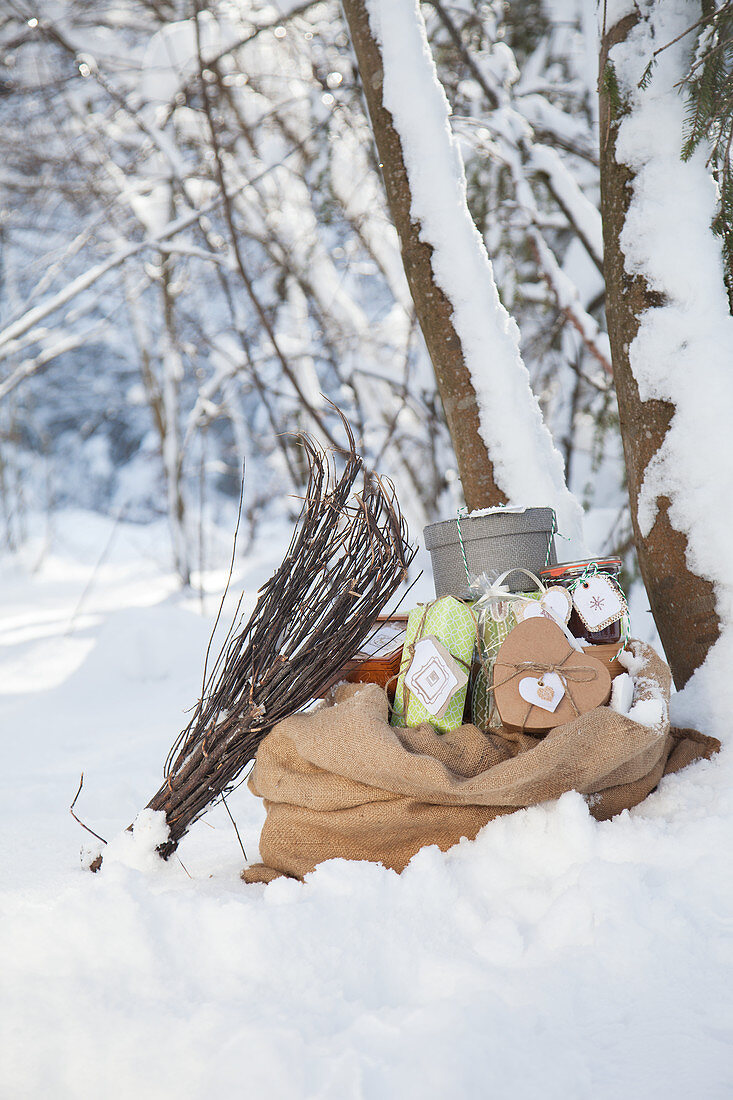 Reisigbesen lehnt am Sack mit Geschenken im Schnee