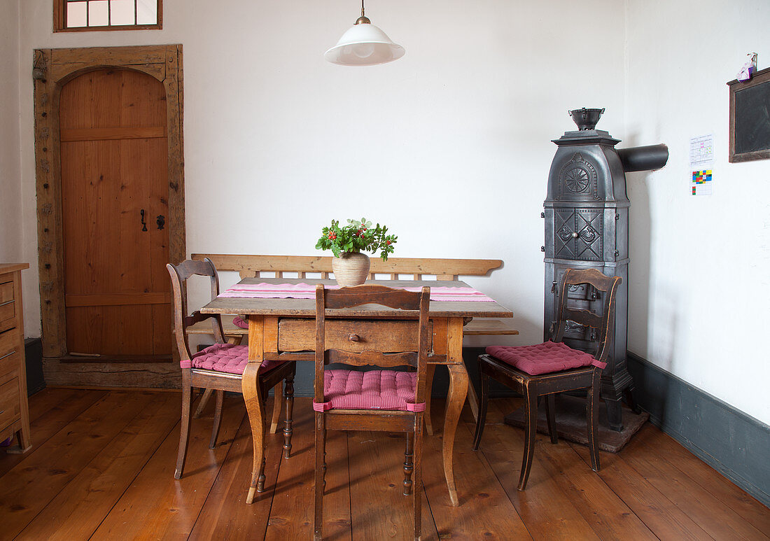 Biedermeier chairs around wooden table next to old iron stove