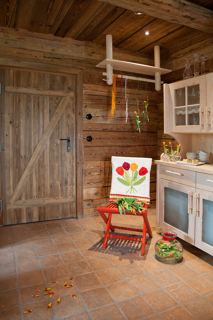 Mit Tulpen bestickte Husse auf einem roten Stuhl in der Landhausküche