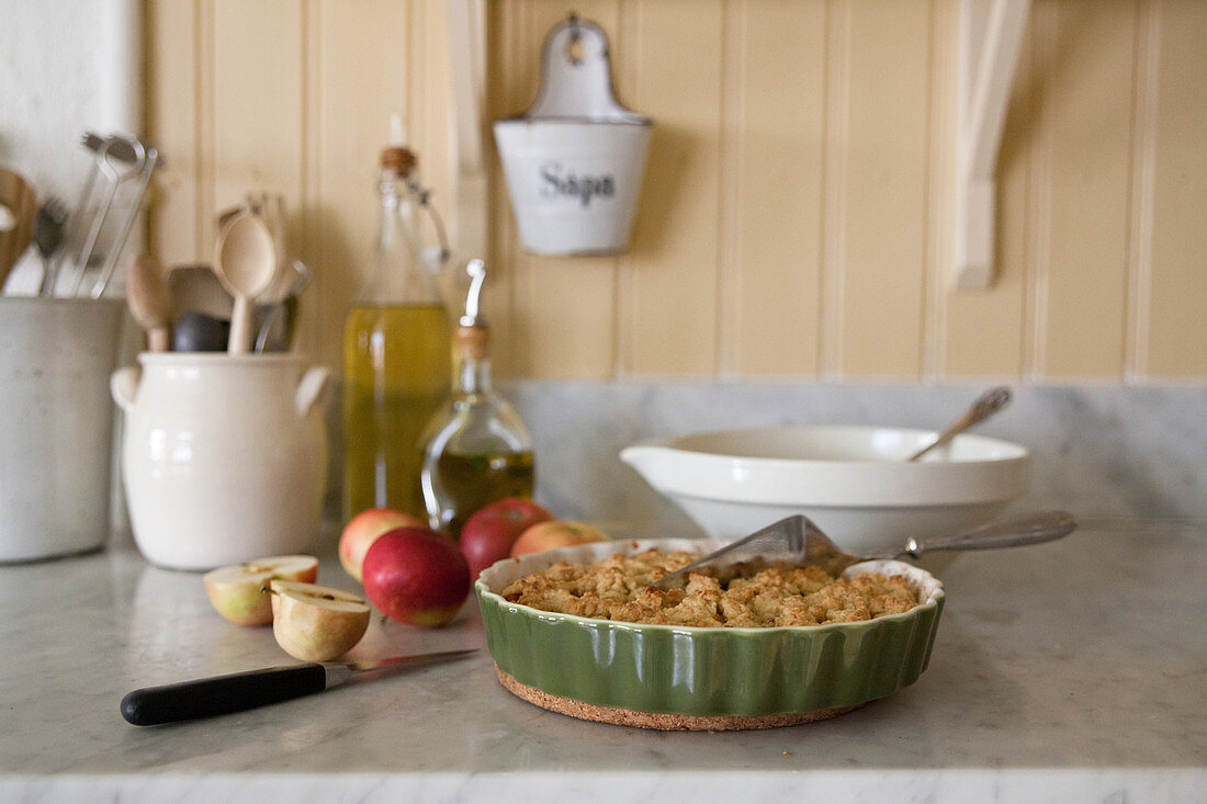 Äpfel und Kuchen in der Terrine auf der Marmorplatte in der Küche