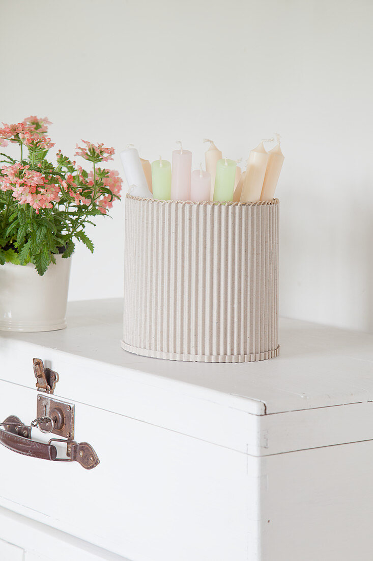 Pastel candles in container made from corrugated cardboard