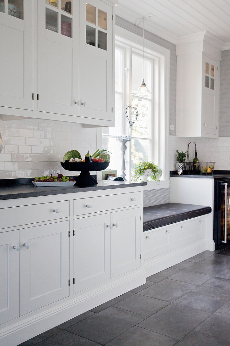 White panelled cabinets and grey floor in large, country-house kitchen
