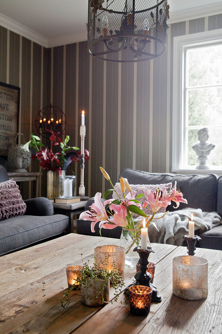 Rosa Lilien und Kerzendeko auf dem Couchtisch im Wohnzimmer