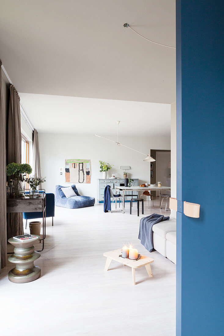 Blue sliding door leading into open-plan interior with sofa and dining table