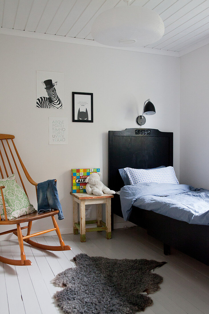 Schaukelstuhl und schwarzes Bett im Kinderzimmer