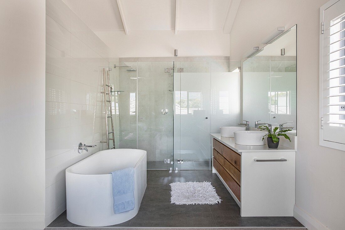 Oval bathtub in modern bathroom with floor-level shower