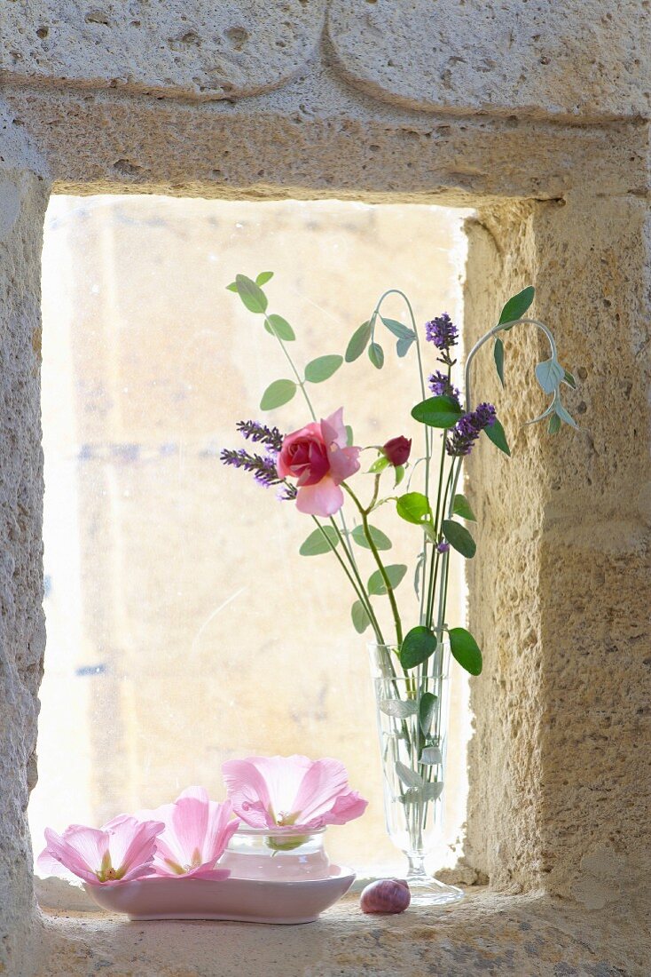 Vase mit zarte Rose und Lavendelblüten auf Fensterbank