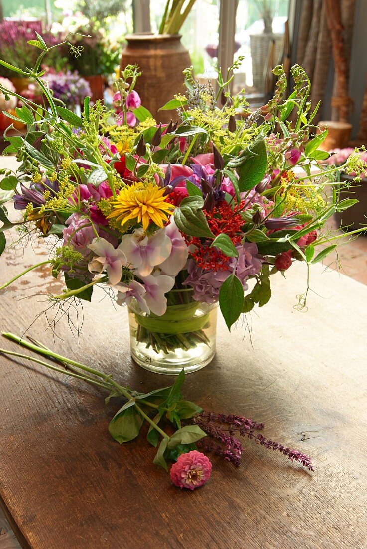 Colourful summer flowers in glass vase on wooden table