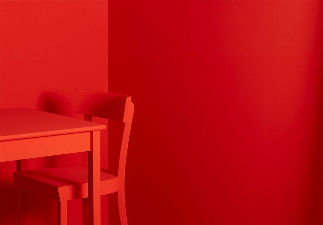 Roter Tisch und roter Stuhl vor roten Wänden