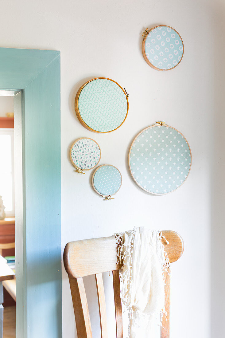 Arrangement of pale blue fabric mounted in embroidery frames on wall