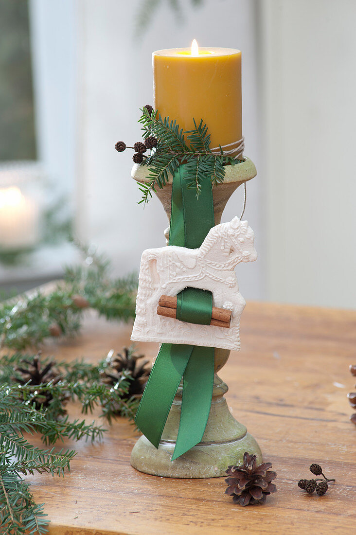 Yellow candle on candle holder with white horse