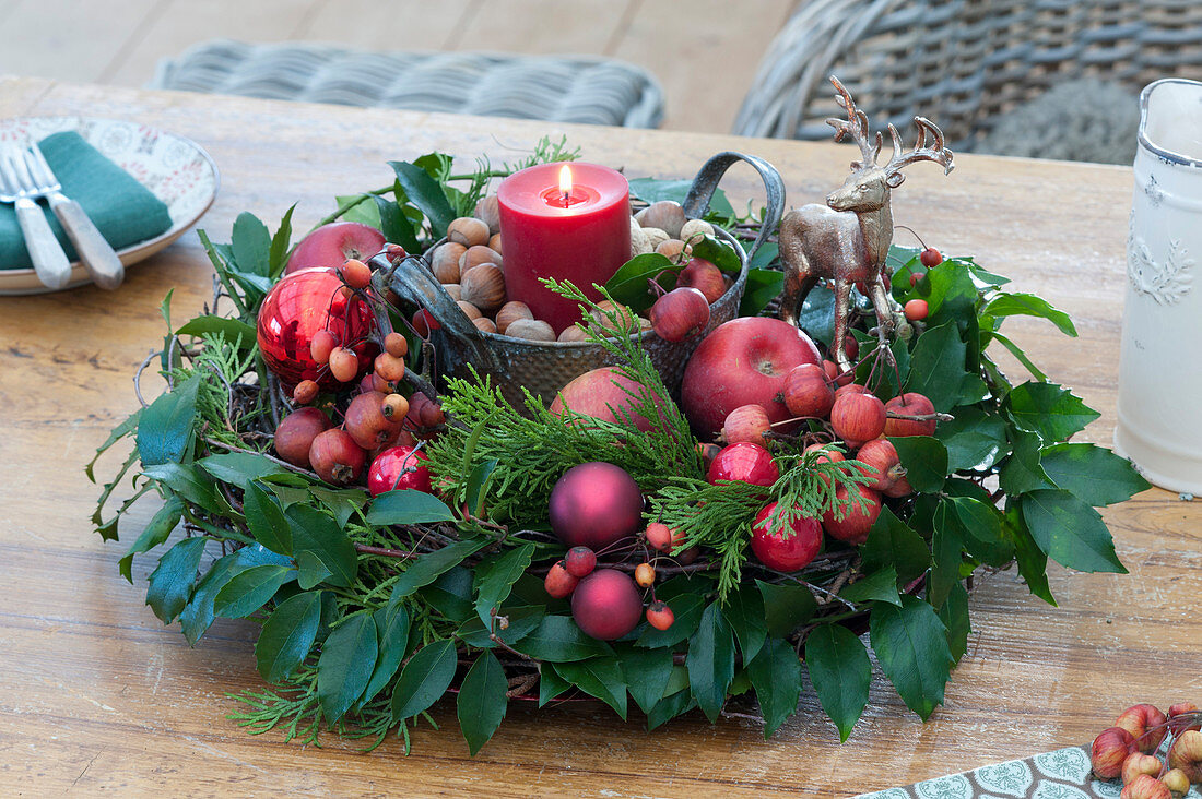 Red candle in a wreath of Ilex and conifers branches