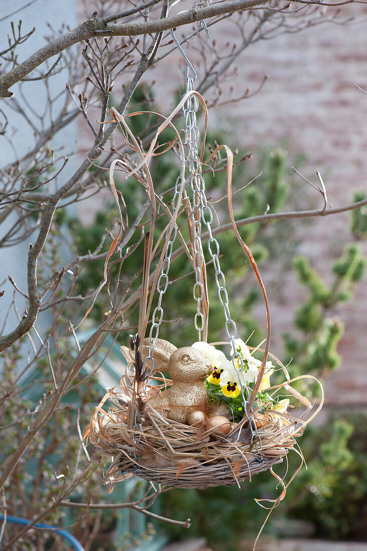 Basket bowl with grass as hanging Easter nest with easter bunny and easter eggs