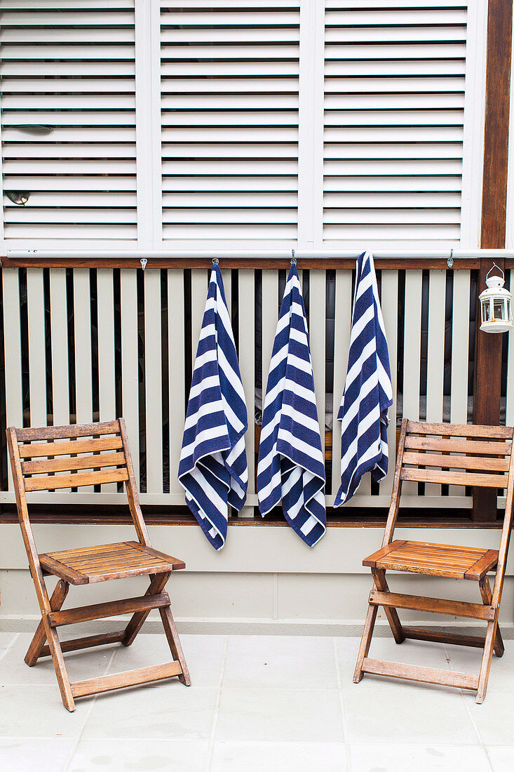 Hanging towels and two wooden folding chairs at the pool edge