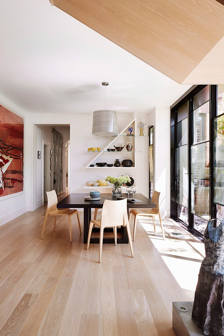 Bright dining room in designer style with wooden floor and window front