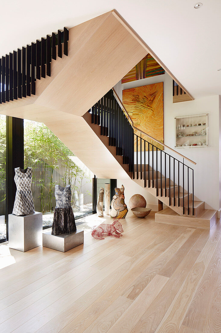 Skulpturensammlung auf dem hellen Holzboden unter der Treppe