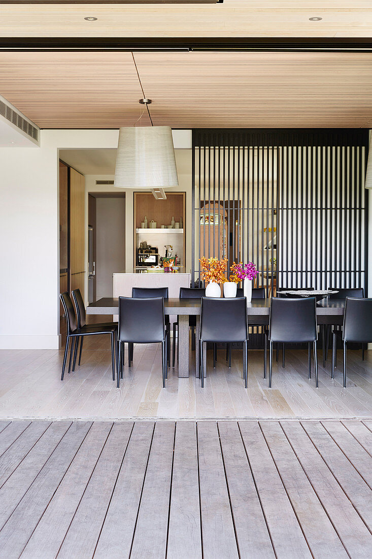 Black chairs around the table in the dining room with an open wall