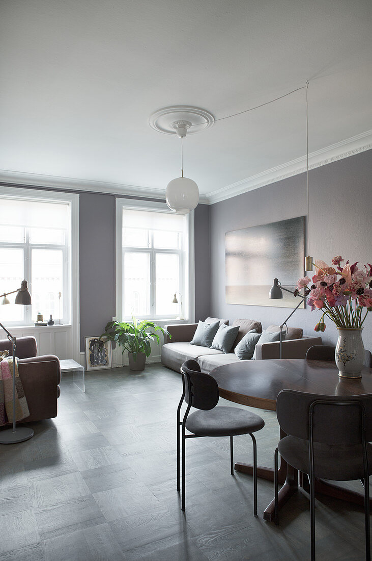 Sofa behind flowers on dining table in living room in shades of grey