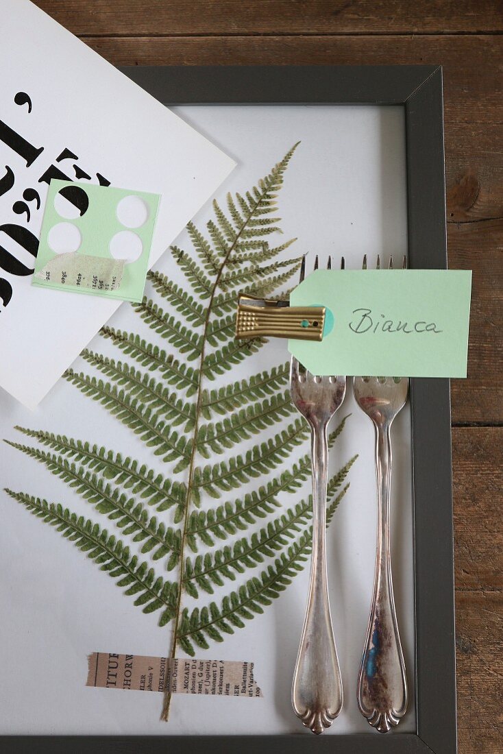 Pressed fern leaf in frame with place card