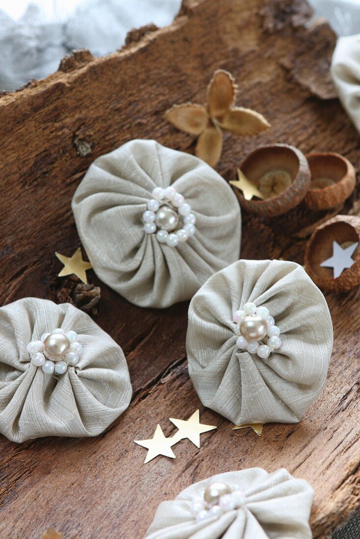 Small fabric rosettes with beads and gold stars on piece of bark