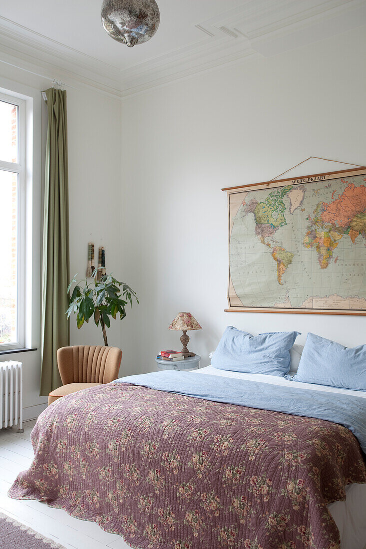 Old map of the world on wall above bed in vintage bedroom