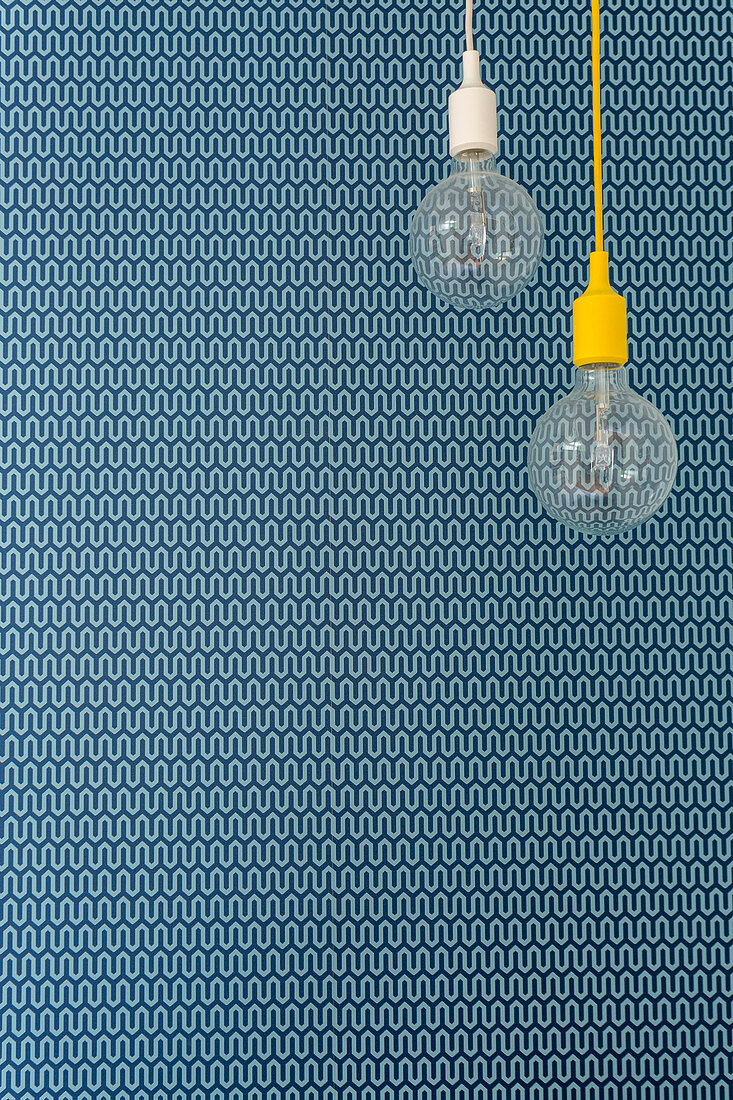 Two pendant lamps in front of blue patterned wallpaper