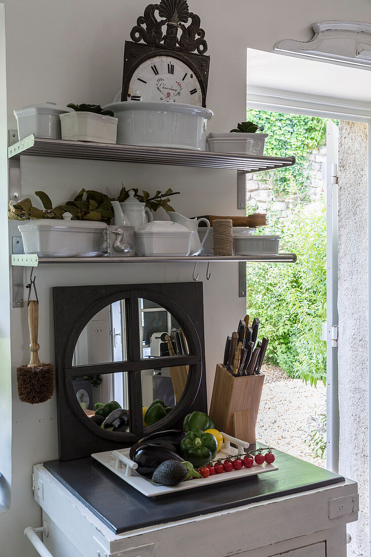 Regal mit Geschirr, Spiegel, Messerblock und Gemüseplatte in rustikaler Küche