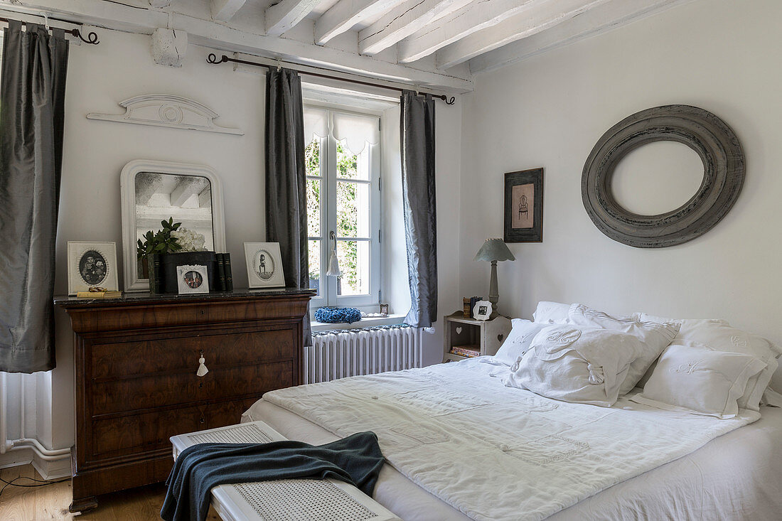 Doppelbett und antike Kommode in rustikalem Schlafzimmer