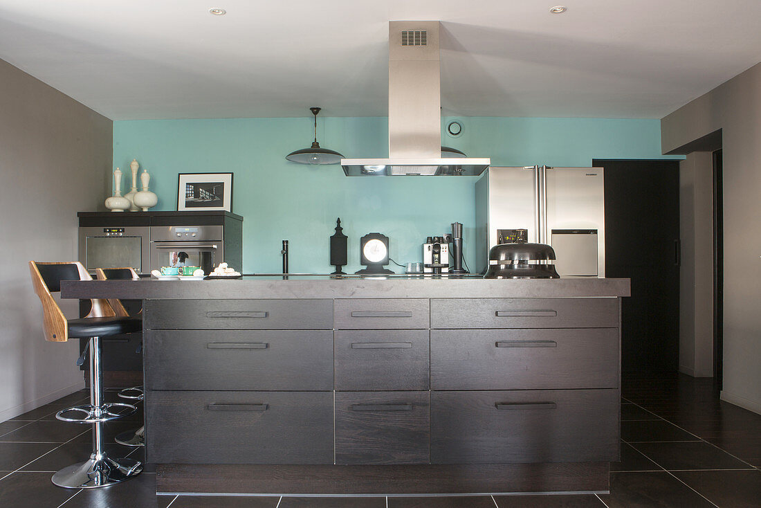 Modern, open-plan kitchen with black cabinets and pale blue wall