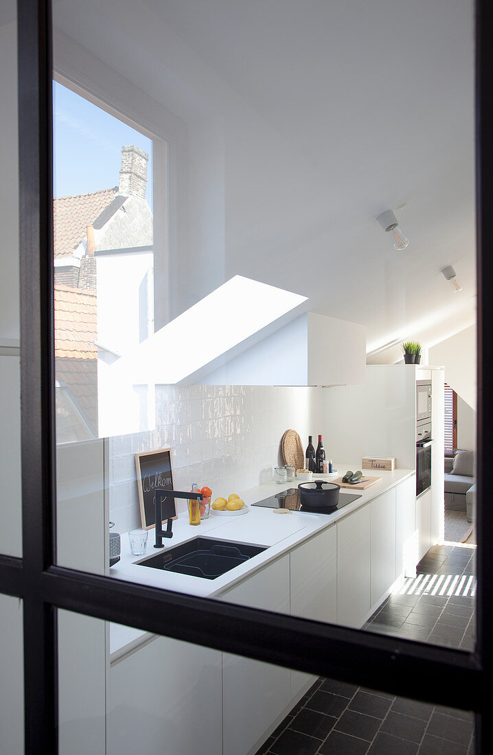View into white fitted kitchen through glass door