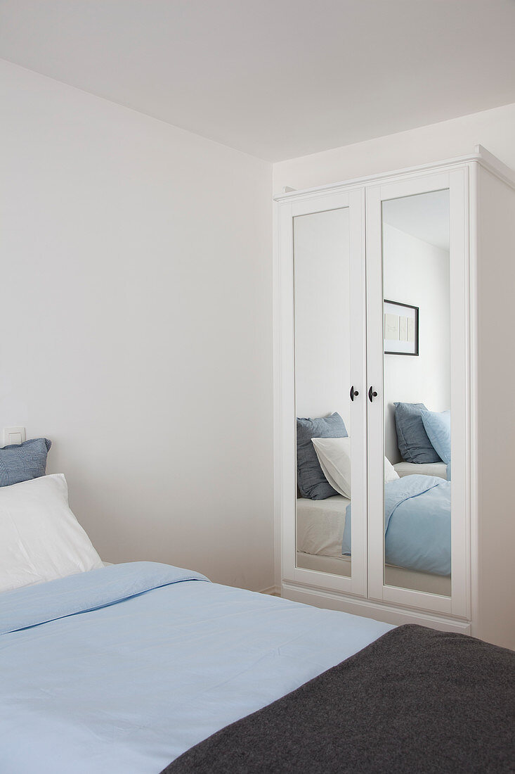 Einzelbett und Kleiderschrank mit Spiegeltür im Gästezimmer