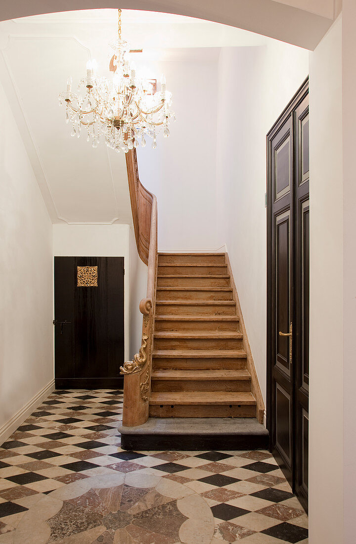 Foyer with tiled floor, wooden staircase and chandelier