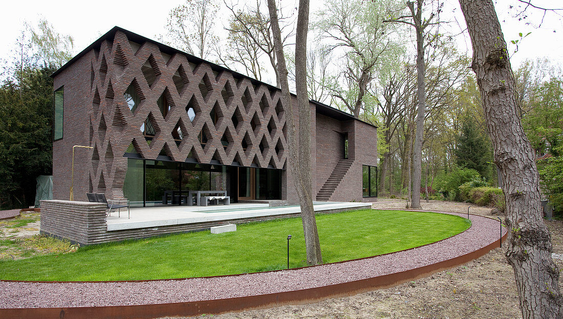 Semicircular lawn in front of modern, architect-designed brick house with diamond-shaped apertures in façade