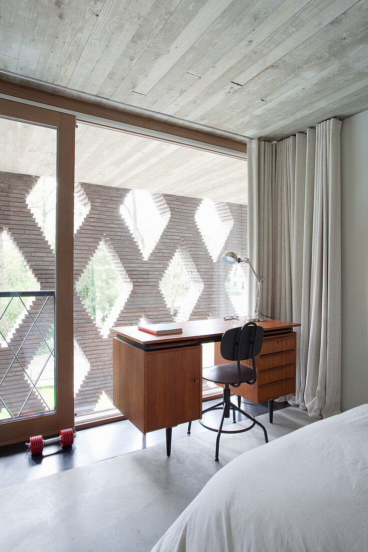 Desk in bedroom with glass wall and perforated façade