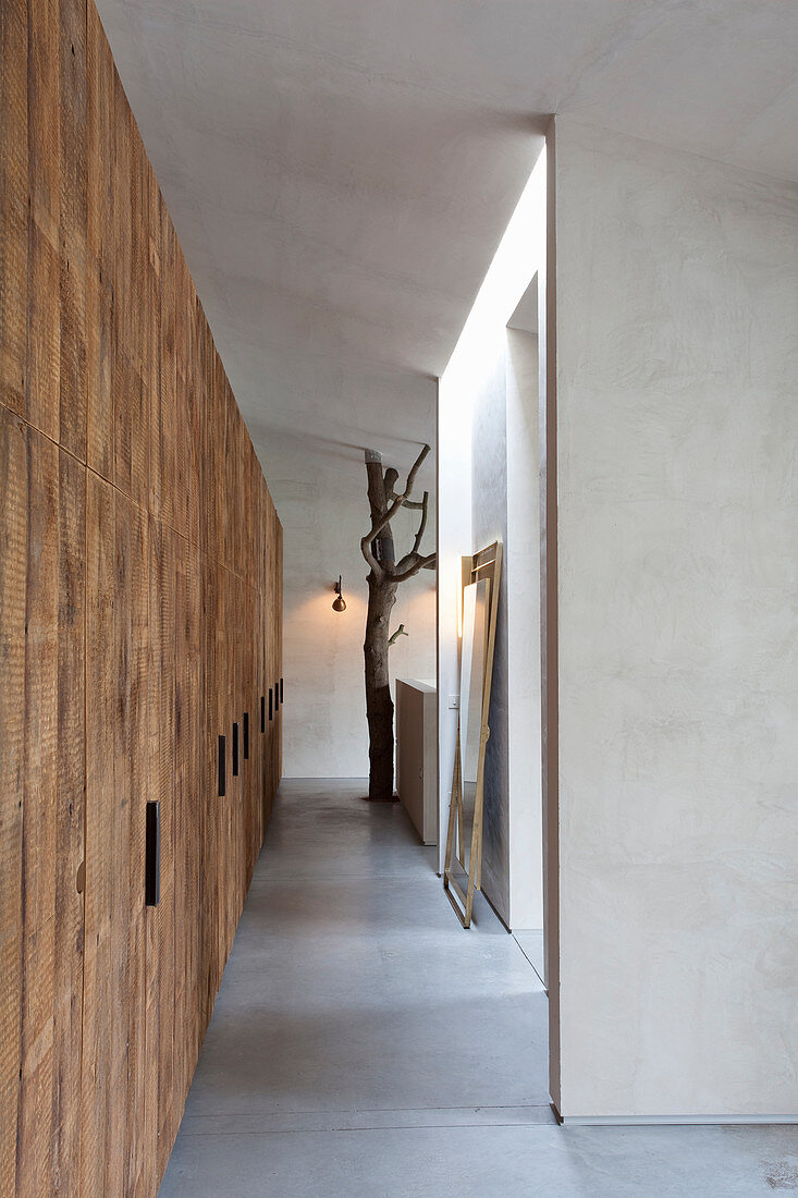 Rough wooden fitted cupboards in corridor with concrete floor