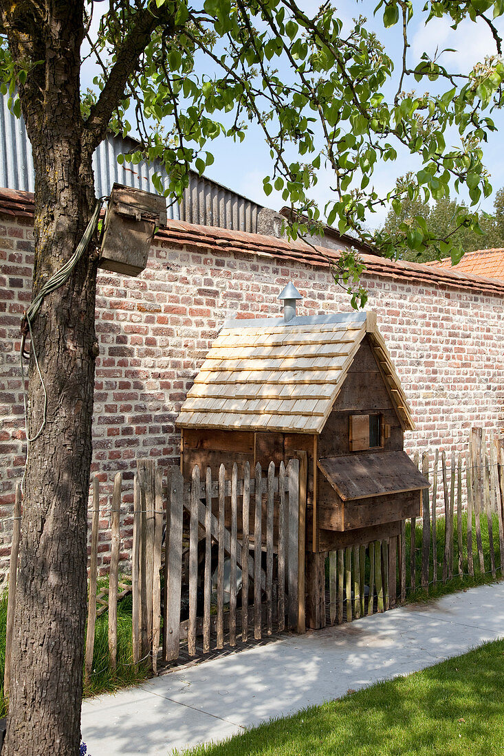 Wooden chicken coop against brick garden wall