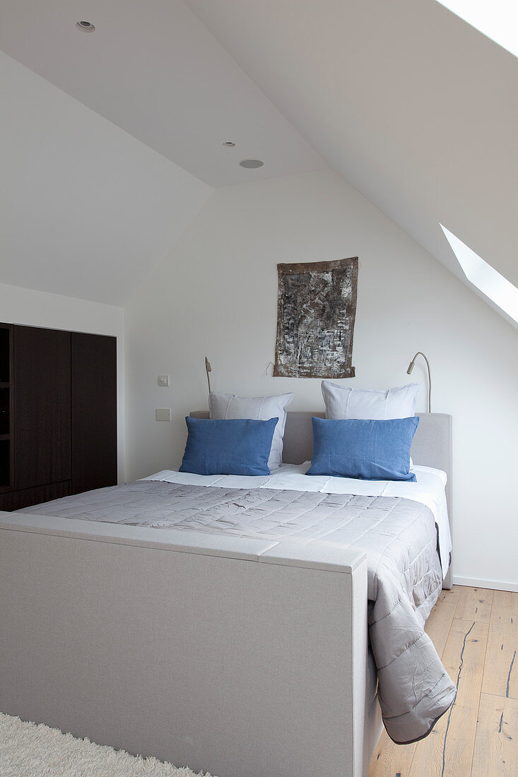 Small attic bedroom with blue pillows on bed