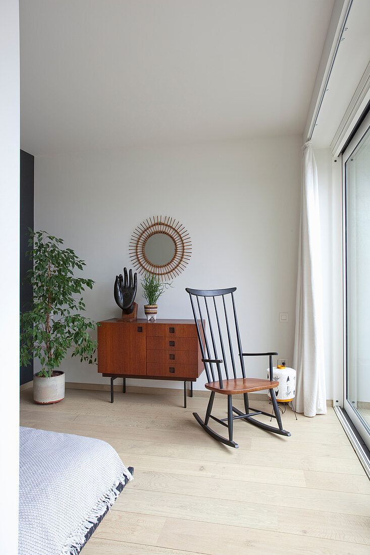 Retro sideboard and rocking chair in front of terrace doors in bedroom